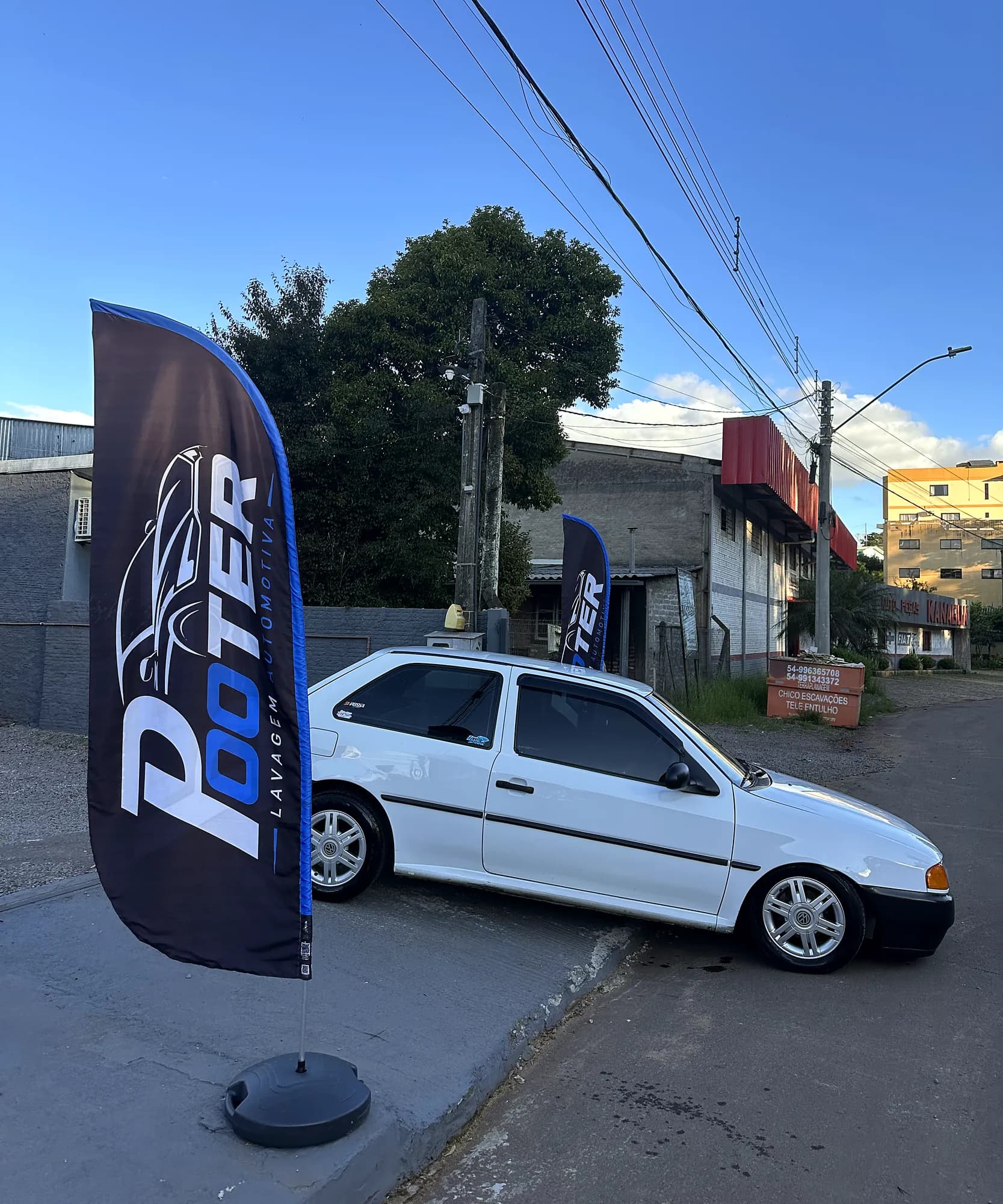VW Gol branco limpo ao lado do wind banner da Pooter Lavagem Automotiva em Marau-RS